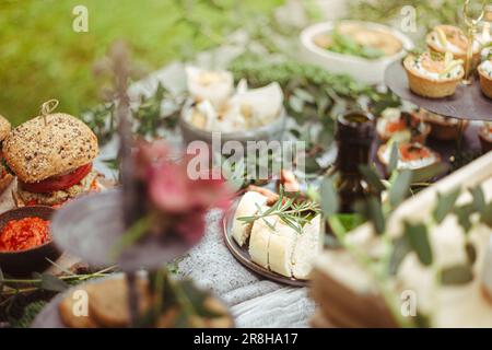 Rustikaler Außenempfang in elegantem Garten mit lokalen Gourmetspeisen. Weibliche Hand gießt natives Olivenöl Ofen Antipasti. Italienische Hochzeit Stockfoto