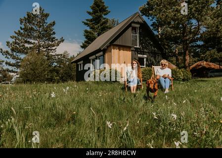 Zwei Frauen, die mit Dog im Front Weekend House spielen Stockfoto