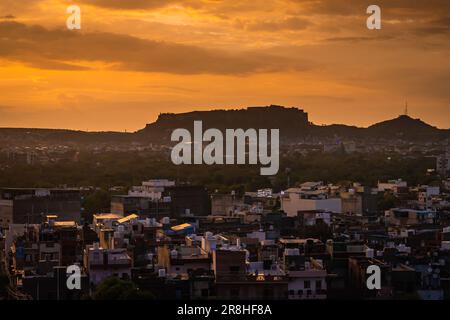 Dramatischer Sonnenuntergang am orangefarbenen Himmel mit Blick auf die Stadt vom Berggipfel am Abend Stockfoto