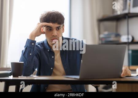 Gelangweilter Typ Aus Dem Nahen Osten, Der Im "Laptop Hasst Job Indoors" Sitzt Stockfoto