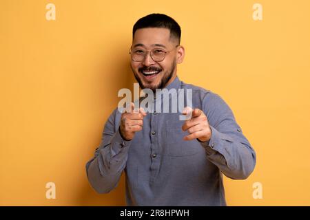 Ich Hab Dich. Fröhlicher, Gutaussehender Asiatischer Mann, Der Mit Zwei Händen Vor Die Kamera Klopft Stockfoto