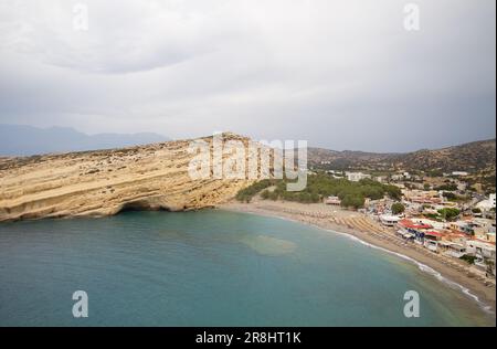 Blick auf Matala, Kreta, mit Strand und Meer, umgeben von Kalksteinfelsen mit Höhlen auf der Westseite, aus Kalkstein geschnitzt Stockfoto