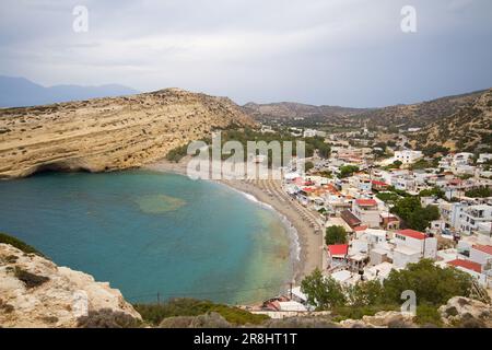 Blick auf Matala, Kreta, mit Strand und Meer, umgeben von Kalksteinfelsen mit Höhlen auf der Westseite, aus Kalkstein geschnitzt Stockfoto