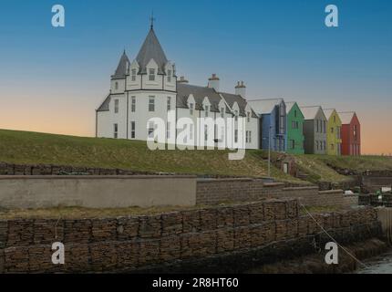 John O'Groats, Schottland, Großbritannien - Mai 7. 2023 - Weißes Gebäude mit Revolver in John O'Groats mit verschiedenen bunten Gebäuden in der Nähe Stockfoto