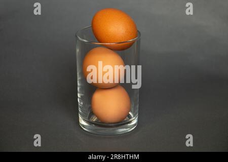 Gelbe Hühnereier in einem glasdurchsichtigen Becher auf dunkelblauem Hintergrund Stockfoto