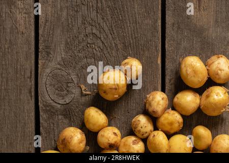 Junge rothaarige, geschälte Kartoffeln liegen aus der Nähe auf einem Holztisch Stockfoto