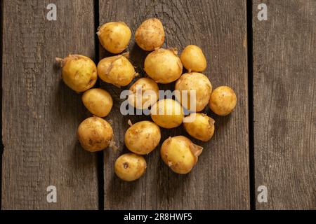 Junge rothaarige, geschälte Kartoffeln liegen aus der Nähe auf einem Holztisch Stockfoto