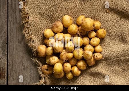 Junge rothaarige, geschälte Kartoffeln liegen aus der Nähe auf einem Holztisch Stockfoto