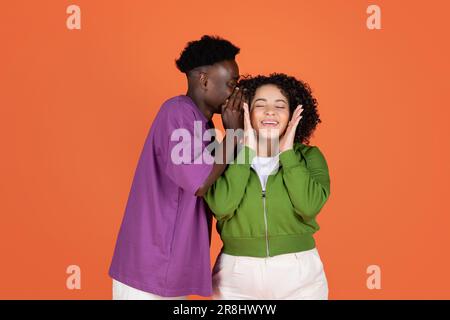 Ein afroamerikanischer Kerl teilt ein Geheimnis mit seiner hispanischen Freundin Stockfoto