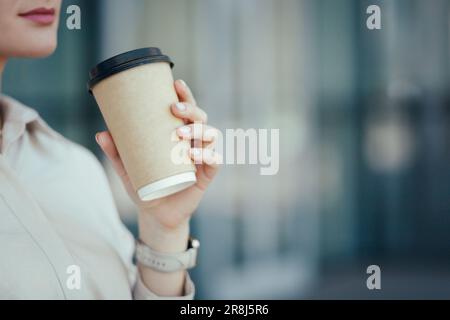 Nahaufnahme einer unbekannten jungen Geschäftsfrau, die einen Pappbecher mit Kaffee zum Mitnehmen oder einem anderen Getränk in der Hand hält Stockfoto