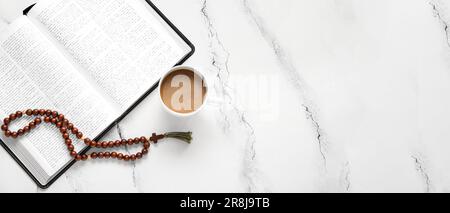 Heilige Bibel, Tasse Kaffee und Gebetsperlen auf hellem Hintergrund mit Platz für Text Stockfoto