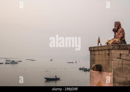 Ein heiliger Mann meditiert auf den Ghats mit Blick auf den Ganges in Varanasi, Indien Stockfoto