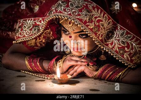 Eine junge Frau in einem Hochzeitssari posiert mit Ghee-Lampen vor DEV deepawali in Varanasi, Indien. Stockfoto