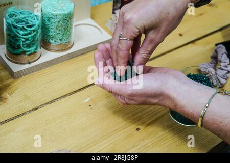 Die Hand einer Person, die während der Revolution Plastics Future Conference der Universität Portsmouth in Portsmouth recycelte Plastikpellets aus verlassenen Fischernetzen hielt, die an den Küsten von Cornwall, Newquay, gesammelt wurden. Waterhaul, ein in Großbritannien ansässiges Sozialunternehmen in Cornish, bekämpft die Plastikverschmutzung durch weggeworfene Fanggeräte, indem es diese in recycelte Sonnenbrillen umwandelt. Die internationale Plastics Future Conference wurde veranstaltet, um globale Forschung und Innovation über verschiedene Disziplinen und Gemeinschaften hinweg auszutauschen, um das Problem der globalen Kunststoffverschmutzung anzugehen. Stockfoto