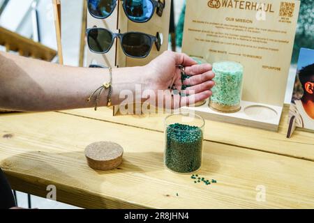 Portsmouth, Großbritannien. 20. Juni 2023. Die Hand einer Person, die während der Revolution Plastics Future Conference der University of Portsmouth in Portsmouth recycelte Plastikpellets aus verlassenen Fischernetzen eingießt, die an den Küsten von Cornwall, Newquay, gesammelt wurden. Waterhaul, ein in Großbritannien ansässiges Sozialunternehmen in Cornish, bekämpft die Plastikverschmutzung durch weggeworfene Fanggeräte, indem es diese in recycelte Sonnenbrillen umwandelt. Die internationale Plastics Future Conference wurde veranstaltet, um globale Forschung und Innovation über verschiedene Disziplinen und Gemeinschaften hinweg auszutauschen, um das Problem der globalen Kunststoffverschmutzung anzugehen Stockfoto