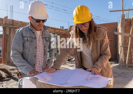 Diversity Portrait männliche und weibliche Ingenieure arbeiten auf dem Dach des Standorts zusammen, beide tragen Schutzhelme. Stockfoto