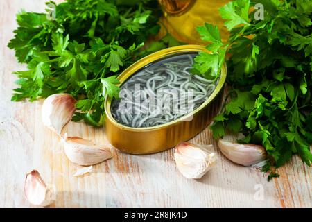 Eingelegte Aale in offener Dose mit Knoblauch am Tisch Stockfoto