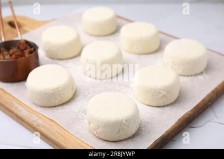 Ungekochte Pfannkuchen mit Hüttenkäse und Rosinen auf weißem Tisch, Nahaufnahme Stockfoto