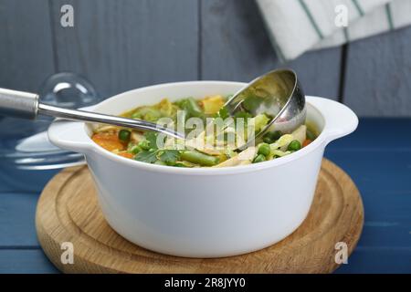 Kochtopf mit köstlicher Gemüsesuppe mit Huhn und Pfanne auf blauem Holztisch Stockfoto