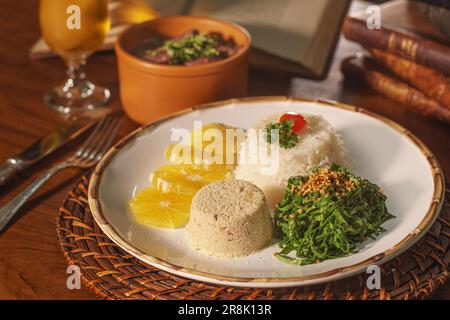 Wunderschönes Gericht mit Feijoada und Bier. Im Hintergrund alte Bücher Stockfoto