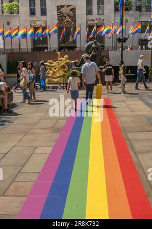 Im PRIDE-Monat Juni 2023 in New York City, USA, spazieren Touristen im Rockefeller Center durch die in Regenbogenfarben bemalten Kanalgärten Stockfoto