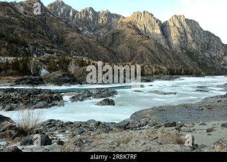 Steinformationen in der Mitte des gefrorenen Beete eines wunderschönen Bergflusses an einem bewölkten Winterabend. Katun, Altai, Sibirien, Russland. Stockfoto