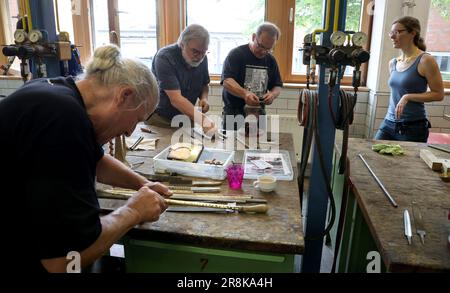 Rostock, Deutschland. 21. Juni 2023. Auf dem 19. Internationalen Workshop für die Trompetenherstellung im Handwerkertrainingscenter bauen die zehn Teilnehmer aus Deutschland, Spanien, Dänemark und den USA eine lange Trompete (ohne Löcher), die auf einem Original von Hans Hainlein aus dem Jahr 1632 unter fachkundiger Anleitung von Michael Münkwitz, Meisterhandwerker in der Herstellung von Metall- und Holzwindgeräten, innerhalb einer Woche. Münkwitzt hat in den letzten Jahren mehr als 850 Werkstattteilnehmer aus der ganzen Welt betreut. Kredit: Bernd Wüstneck/dpa/Alamy Live News Stockfoto