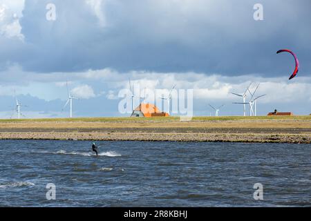 Ein Kitesurfer reitet auf den Wellen in der Nähe des Hafens von Dagebüll. Der Bezirk Dagebüll Hafen (Dagebüll Hafen) befindet sich direkt an der Küste des Wattenmeers. Der Hafen bietet regelmäßige Fährverbindungen zu den charmanten Inseln Foehr und Amrum. Stockfoto