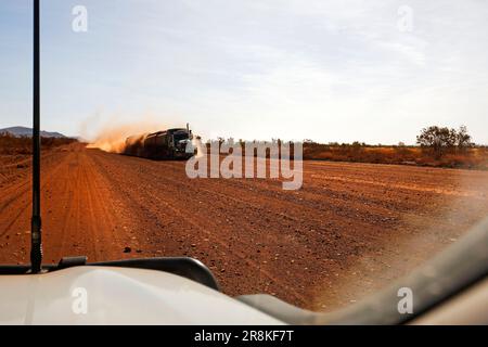 Ein großer Lastwagen nähert sich einem Auto auf einer roten Feldstraße, Pilbara, Westaustralien Stockfoto