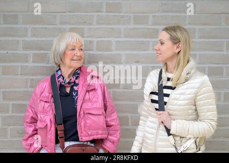 Mutter und Tochter stehen vor einer weißen Mauer und schauen einander an Stockfoto