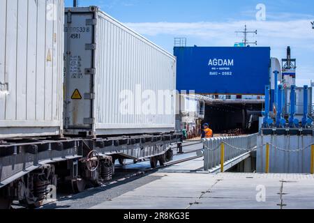 Kuryk, Kasachstan. 21. Juni 2023. Güterwagen mit Containern werden im Fährhafen Kuryk auf ein Fährschiff verladen und über das Kaspische Meer transportiert. Für den Güterverkehr zwischen Asien und Europa gewinnt der so genannte mittlere Korridor zunehmend an Bedeutung. Die Route verläuft durch Zentralasien und umgeht Russland im Norden und den Iran im Süden. Kredit: Jens Büttner/dpa/Alamy Live News Stockfoto