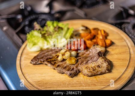 Beef Steak auf einem Holztablett, Hintergrund für Werbung und Tapete in der Koch- und Essensszene. Echtes Foto in Dekorationsideen Stockfoto