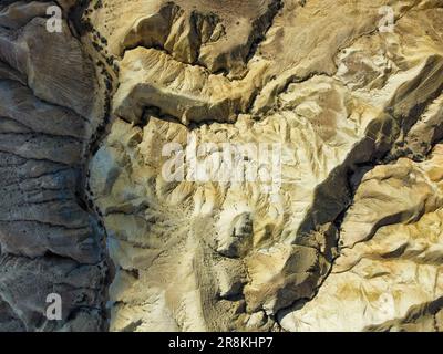 Luftaufnahme auf eine felsige Wüstenlandschaft in der Region Sde Boker von Israel, mit kargem Gelände und hügeligen Felsformationen sichtbar Stockfoto