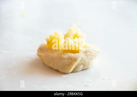 Der Prozess der Herstellung von Kuchen mit Kartoffeln zu Hause in der Küche auf einem weißen Tisch, hausgemachte Gewohnheiten mit Kartoffeln Stockfoto