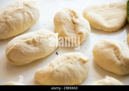 Rohe Pasteten mit Kartoffeln auf einem weißen Tisch in der Küche, hausgemachte Pasteten Stockfoto