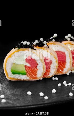 Sushi-Brötchen in Mamenori mit Thunfisch, Lachs, Avocado, Frischkäse und schwarzem Tobiko Stockfoto
