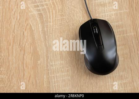 Schwarze kabelgebundene Computermaus auf einem Holztisch in Nahaufnahme Stockfoto