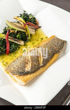 Gegrilltes Seebarschfilet mit Garnierungen in einem eleganten Restaurant Stockfoto