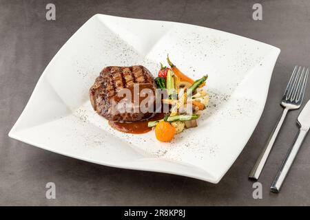 Gegrilltes Rinderfilet mit Demi-Glace-Sauce mit gegrilltem Gemüse auf einem weißen Porzellanteller Stockfoto