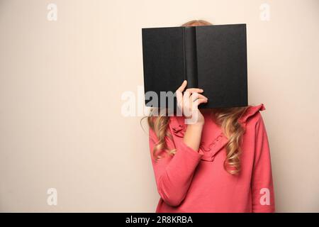 Kleines Mädchen mit Buch auf hellem Hintergrund. Platz für Text Stockfoto