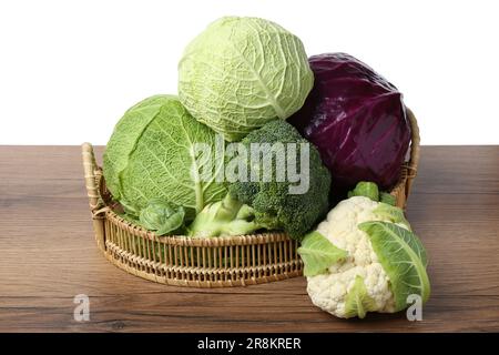 Weidenschale mit verschiedenen Arten von Frischkohl auf Holztisch vor weißem Hintergrund Stockfoto