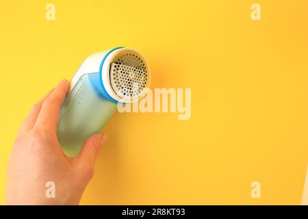 Frau mit modernem Stoffrasierer auf gelbem Hintergrund, Nahaufnahme. Platz für Text Stockfoto