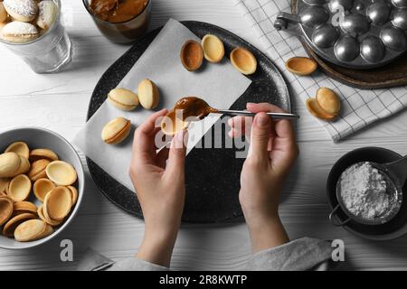 Frau, die leckere walnussförmige Kekse am weißen Holztisch macht, Draufsicht Stockfoto