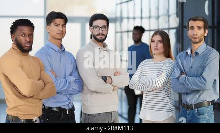 Eine Gruppe erfolgreicher Geschäftsleute, die in Reihe stehen und vor der Kamera auf das Büro schauen Stockfoto