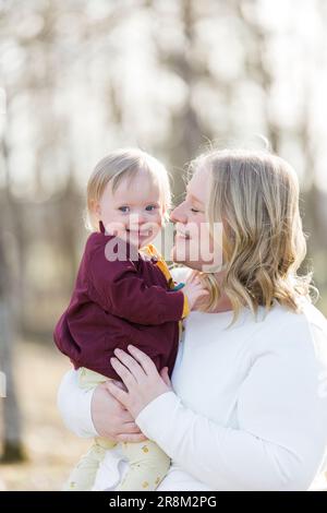 Mutter hält lächelndes Baby mit Down-Syndrom Stockfoto