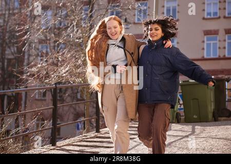 Weibliche Freunde gehen zusammen durch unsere Türen auf dem Fußweg in der Stadt Stockfoto