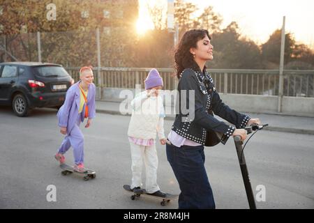 Junge Frauen und Jungen, die zusammen Skateboarden Stockfoto