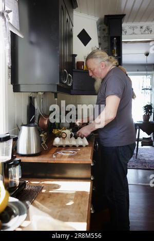 Seitenansicht eines erwachsenen Mannes in der Küche, der Essen zubereitet Stockfoto