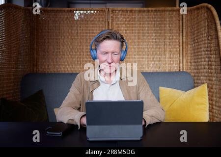 Senior-Mann mit Kopfhörern, der ein Tablet verwendet Stockfoto