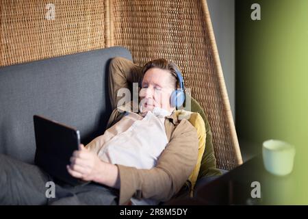 Seniorenmann mit Kopfhörern, der ein Tablet benutzt Stockfoto